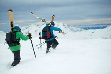 Landschaft mit zwei männlichen Skifahrern, die in Richtung Berg stapfen, Rückansicht, Alpe-d'Huez, Rhone-Alpes, Frankreich - CUF49706