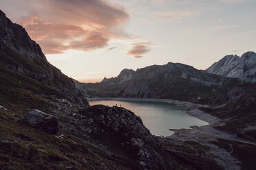 Scenic view of lake amidst mountain ranges against cloudy sky during sunset - CAVF63044