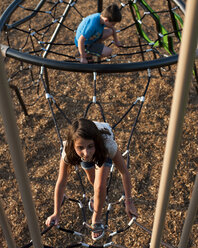 High angle view of siblings playing on jungle gym at playground - CAVF63131