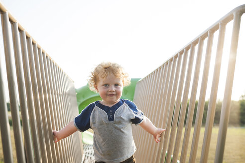 Porträt eines niedlichen kleinen Jungen, der auf einem Spielplatz an einem Spielgerät im Freien spielt - CAVF63132