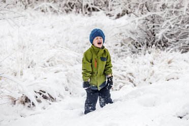 Boy crying while standing on snow covered field - CAVF63149