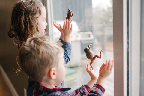 Kinder spielen mit Fröschen am Fenster, lizenzfreies Stockfoto