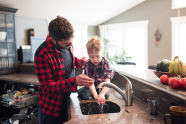 Vater beobachtet Sohn beim Händewaschen in der Küchenspüle - ISF21016