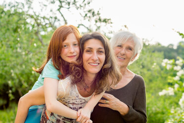 Girl getting piggyback with mother and grandmother in garden, portrait - ISF21046