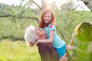 Mädchen wird von Großmutter getragen, mit Mutter im Garten - ISF21049