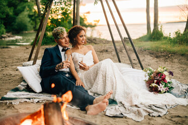 Braut und Bräutigam auf einer Picknickdecke am Lagerfeuer am See, Ontariosee, Toronto, Kanada - ISF21056