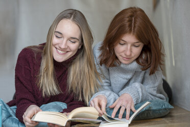 Zwei Freunde liegen Seite an Seite auf dem Boden und lesen Bücher - LBF02410