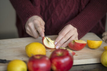 Hände einer jungen Frau, die Früchte auf einem Holzbrett schneiden, Nahaufnahme - LBF02417