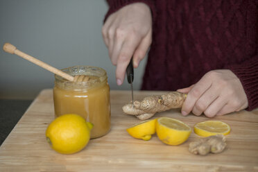 Hands of young woman cutting ginger root on wooden board - LBF02421