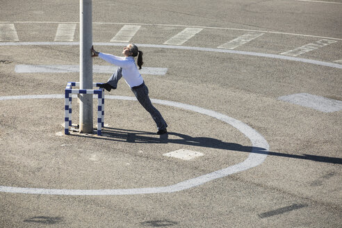 Senior woman doing pilates exercise on a road - GRSF00086