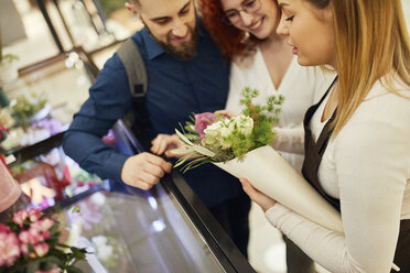 Florist verpackt Blumen für ein Paar im Blumenladen - ZEDF01969