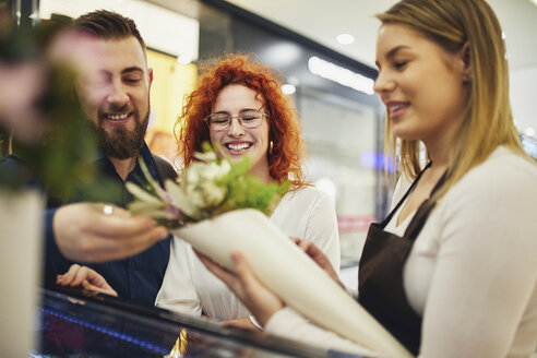 Florist verpackt Blumen für ein Paar im Blumenladen - ZEDF01970