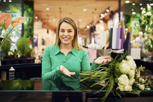 Porträt einer lächelnden Floristin, die einen Blumenstrauß in einem Blumenladen präsentiert - ZEDF01986