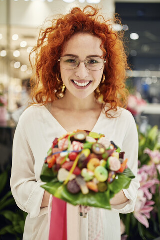 Porträt einer lächelnden Frau, die in einem Geschäft einen Bonbonstrauß hält, lizenzfreies Stockfoto