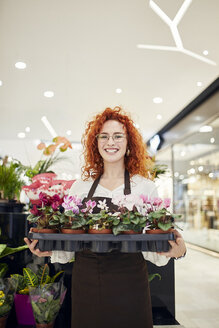 Porträt einer lächelnden Floristin mit einem Tablett voller Topfpflanzen in einem Blumenladen - ZEDF02001