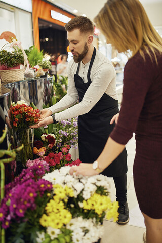 Florist berät Kunde in Blumenladen, lizenzfreies Stockfoto