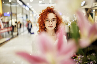 Porträt einer rothaarigen Frau hinter einer Blüte in einer Einkaufspassage - ZEDF02011