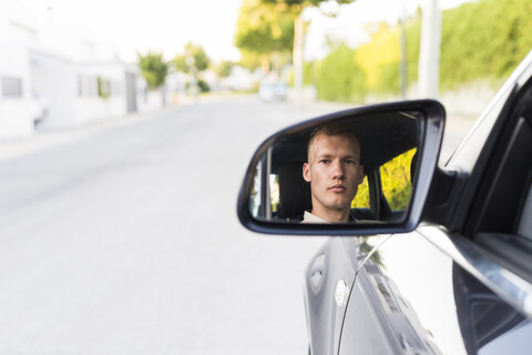 Spiegelung eines jungen Mannes im Außenspiegel eines Autos, lizenzfreies Stockfoto