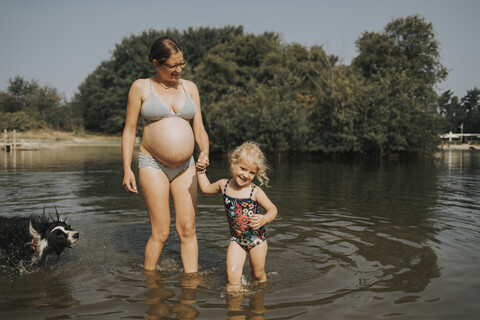 Niederlande, Schiermonnikoog, schwangere Mutter mit Tochter und Border Collie in einem See, lizenzfreies Stockfoto