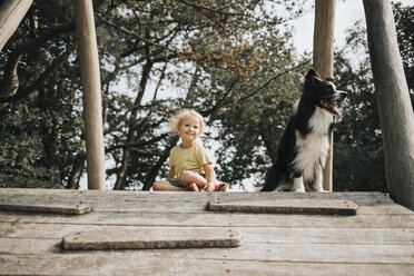 Niederlande, Schiermonnikoog, Mädchen mit Border Collie auf der Promenade im Wald sitzend - DWF00334