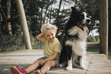 Niederlande, Schiermonnikoog, Mädchen mit Border Collie auf der Promenade im Wald sitzend - DWF00335