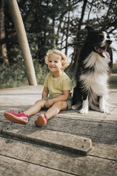 Netherlands, Schiermonnikoog, girl with Border Collie sitting on boardwalk in the forest - DWF00336