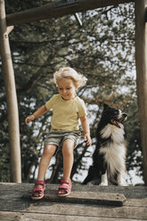 Niederlande, Schiermonnikoog, Mädchen mit Border Collie auf der Promenade im Wald - DWF00338