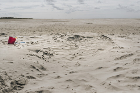 Niederlande, Schiermonnikoog, Strandspielzeug im Sand am einsamen Strand, lizenzfreies Stockfoto