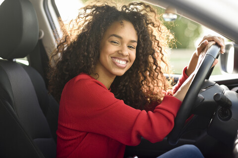 Porträt einer glücklichen jungen Frau in einem Auto, lizenzfreies Stockfoto