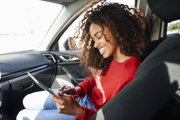 Glückliche junge Frau benutzt Tablet im Auto - JSMF00806