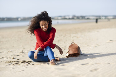 Glückliche junge Frau am Strand sitzend - JSMF00813