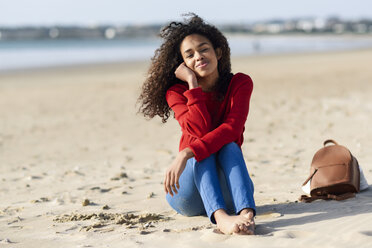 Porträt einer lächelnden jungen Frau, die am Strand sitzt - JSMF00814