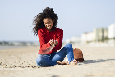 Glückliche junge Frau am Strand sitzend - JSMF00815