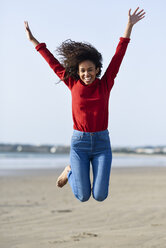 Carefree young woman jumping on the beach - JSMF00821
