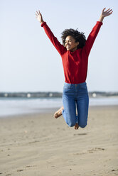 Carefree young woman jumping on the beach - JSMF00822