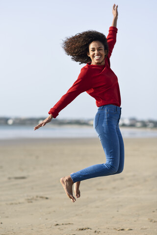 Unbekümmerte junge Frau, die am Strand springt, lizenzfreies Stockfoto