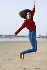 Unbekümmerte junge Frau, die am Strand springt - JSMF00823
