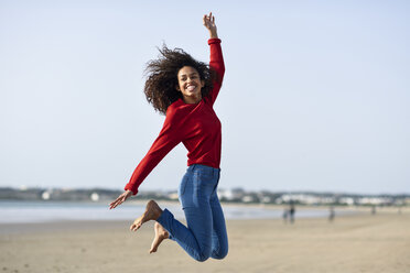 Carefree young woman jumping on the beach - JSMF00824