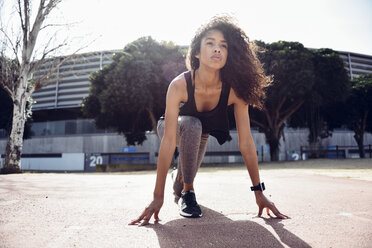 Sporty young woman on tartan track starting - JSMF00831