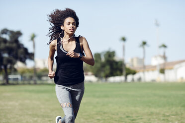 Sporty young woman with earphones running - JSMF00837