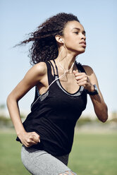 Sportliche junge Frau mit Kopfhörern beim Laufen - JSMF00839