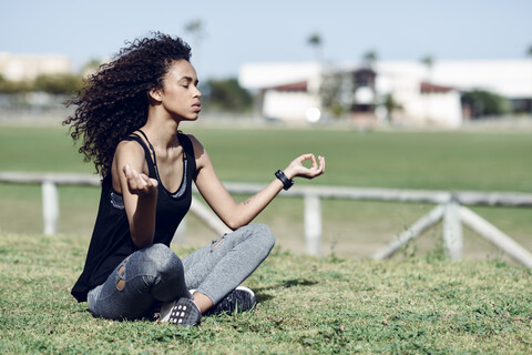 Sportliche junge Frau beim Yoga auf dem Rasen, lizenzfreies Stockfoto