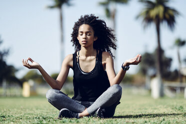 Sporty young woman doing yoga on lawn - JSMF00844