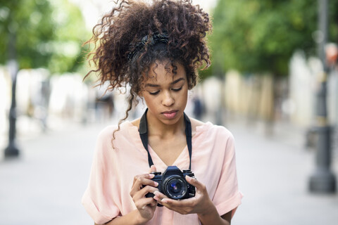 Junge Frau schaut in die Kamera in der Stadt, lizenzfreies Stockfoto