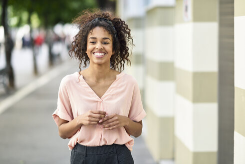 Portrait of smiling young woman in the city - JSMF00870