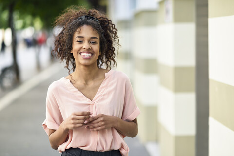 Porträt einer lächelnden jungen Frau in der Stadt, lizenzfreies Stockfoto