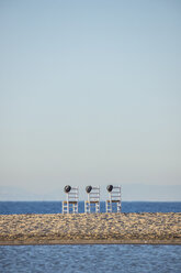 Drei leere Stühle mit Hüten nebeneinander vor dem Meer - KBF00593
