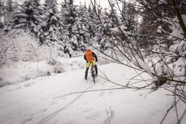 Man with mountainbike on path in winter forest - SEBF00050