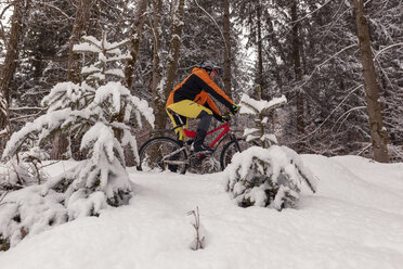 Mann fährt Mountainbike auf einem Weg im Winterwald - SEBF00052