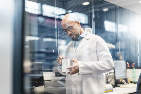 Technician wearing lab coat examining workpiece stock photo